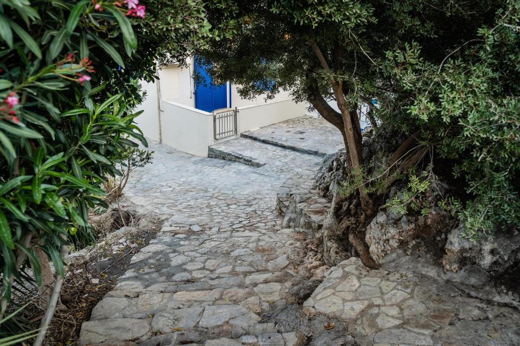 a stone walkway with a tree and a blue door at Theaktis Homes in Kaloi Limenes