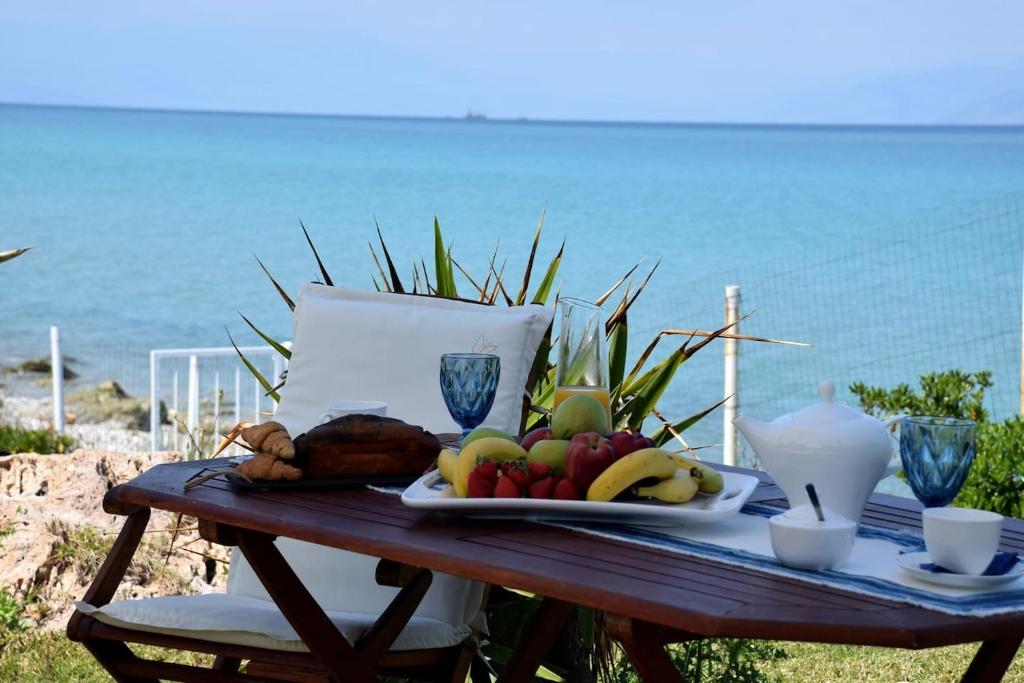 a picnic table with a plate of fruit on the beach at Antorina Beachfront Villas in Kamárion