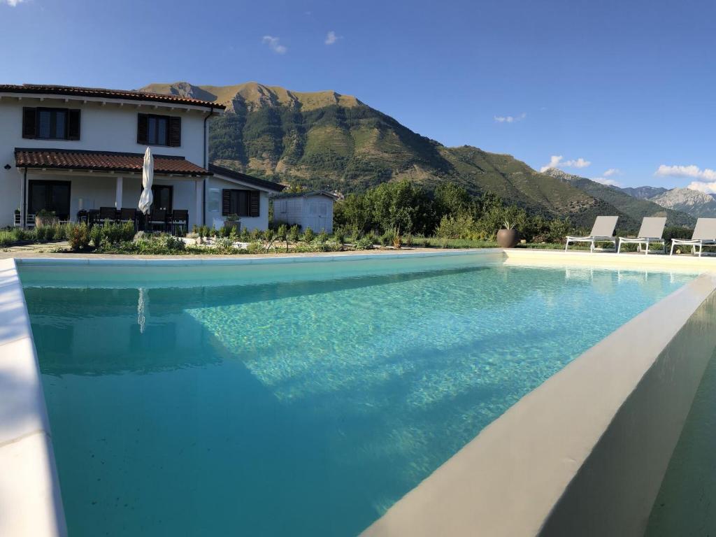 a swimming pool with blue water in front of a house at Luxurious Holiday Home in Bagni di Lucca with Pool in Bagni di Lucca