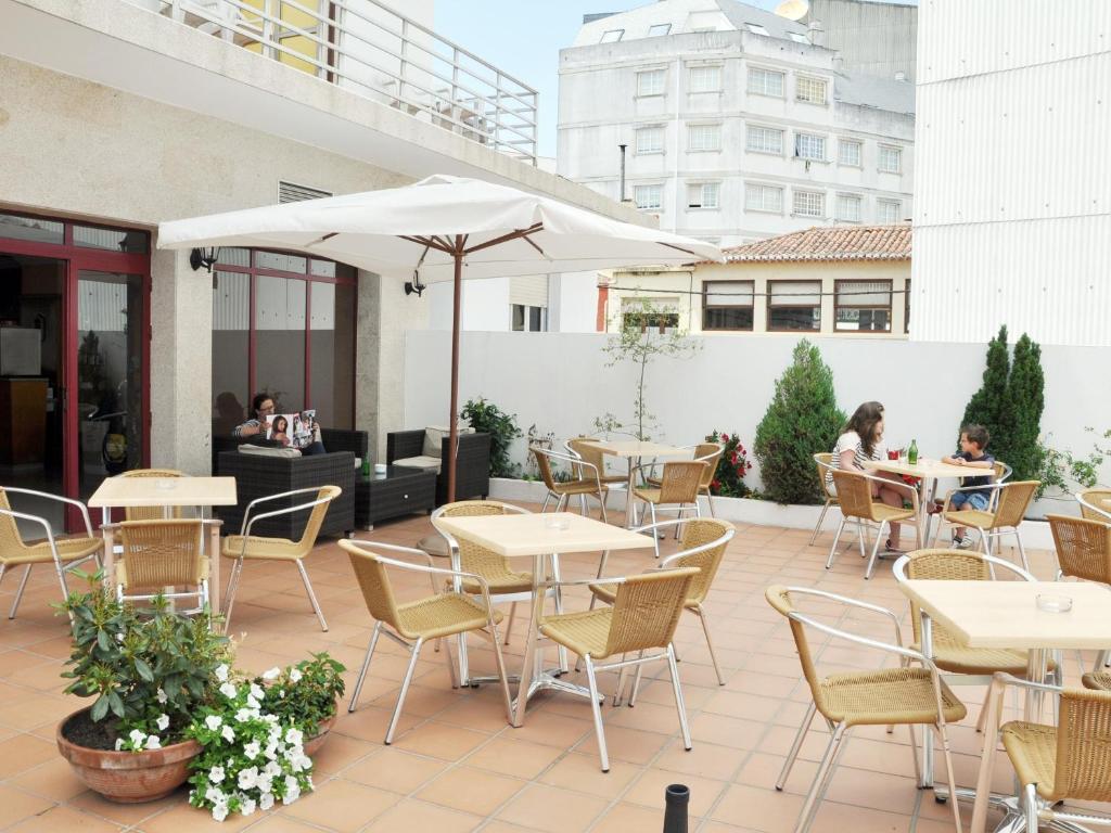 a patio with tables and chairs and people sitting at tables at Hostal Mourelos in O Grove
