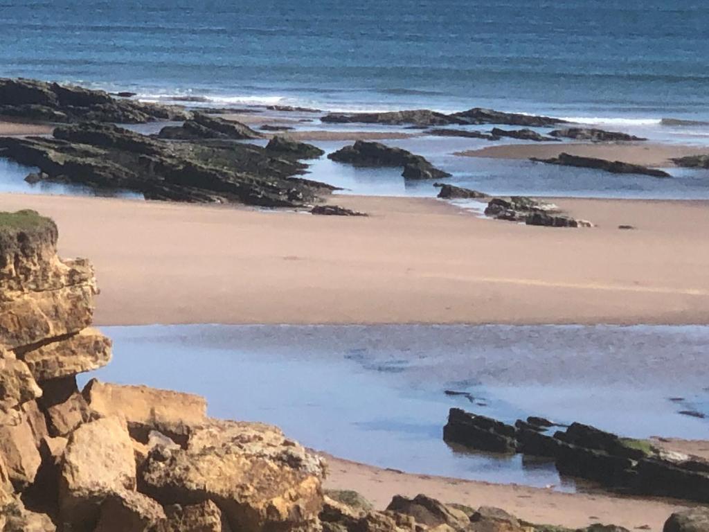 a sandy beach with rocks and the ocean at The Old Vicarage in Berwick-Upon-Tweed