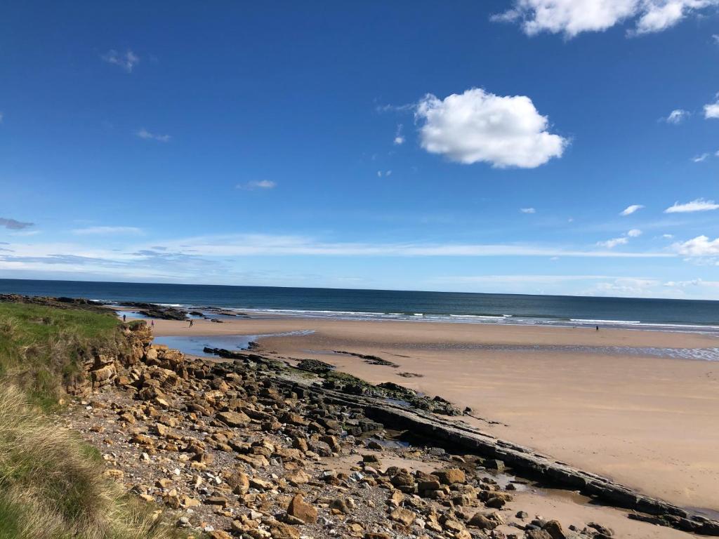 a beach with rocks and the ocean on a sunny day at The Old Vicarage in Berwick-Upon-Tweed