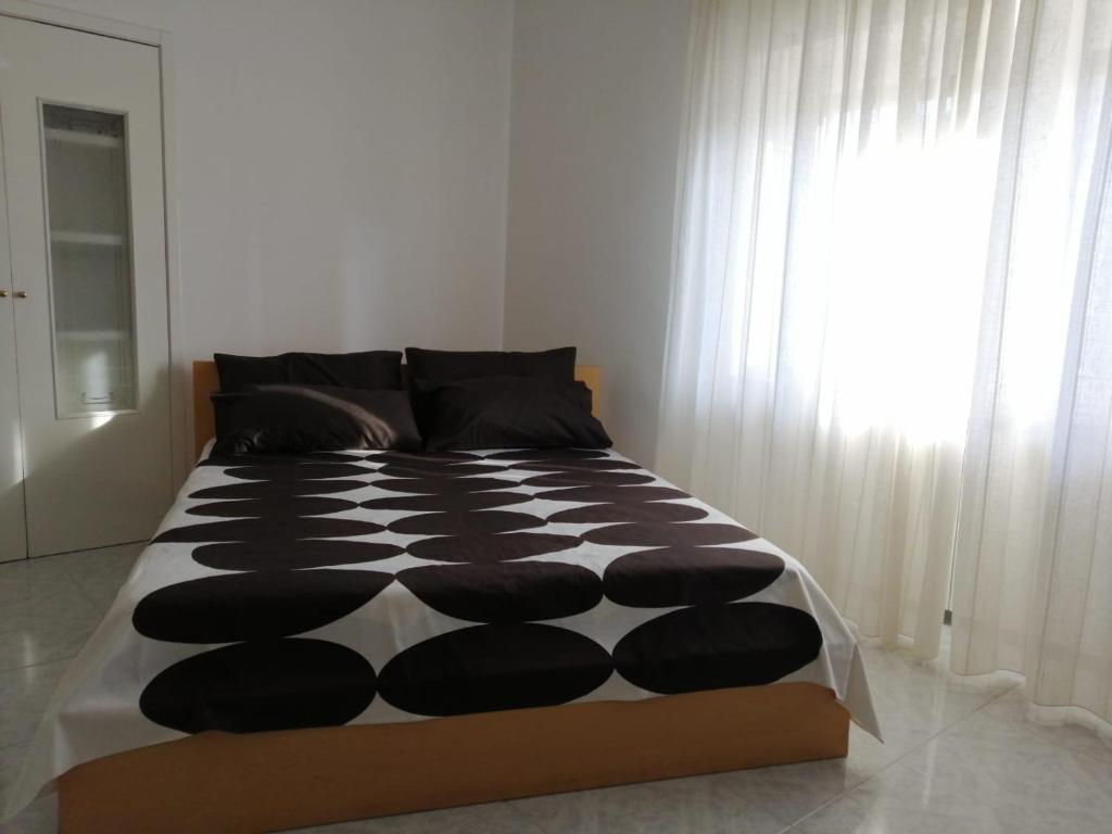 a bed with a black and white comforter and a window at Casa Grazia in Crispiano