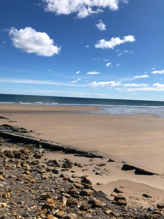 a beach with rocks on the sand and the ocean at The Old Vicarage in Berwick-Upon-Tweed