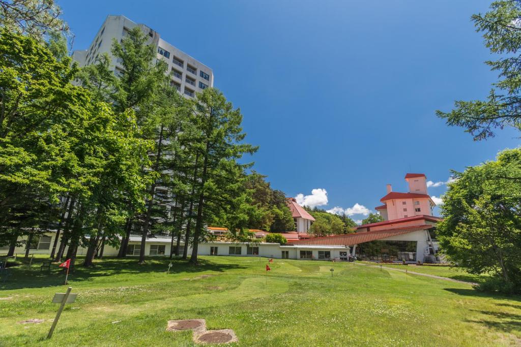 a park with trees and a building in the background at Kusatsu Onsen Hotel Village in Kusatsu
