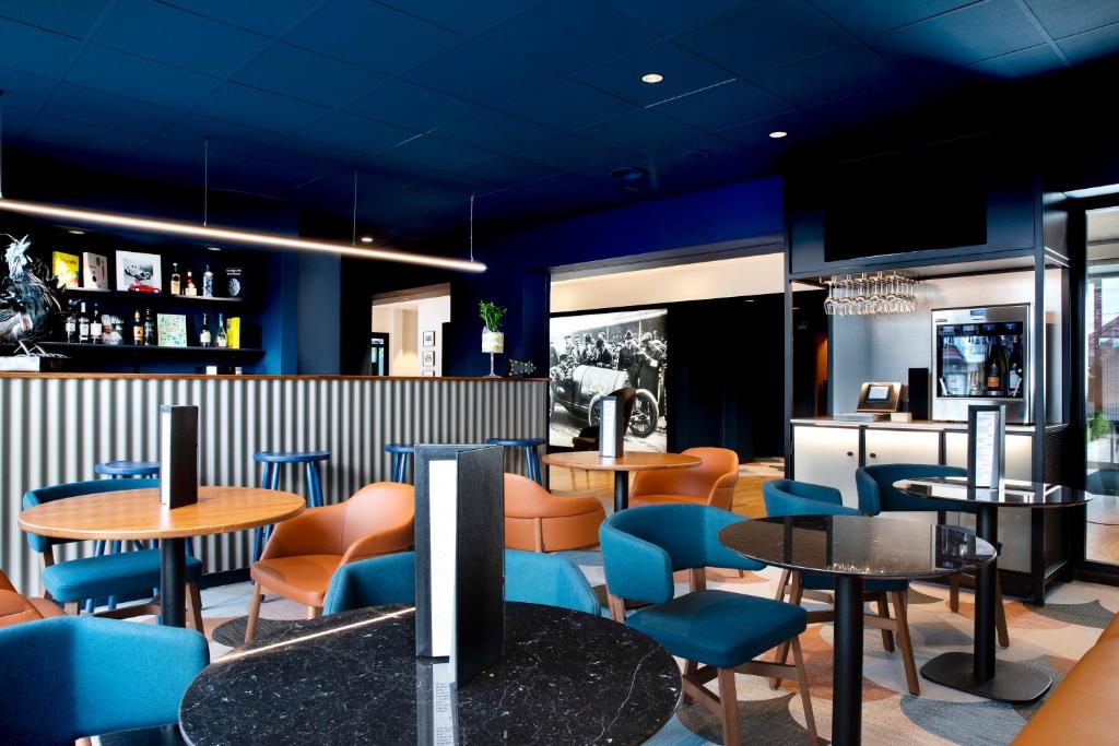 ein Restaurant mit Tischen und Stühlen und blauen Stühlen in der Unterkunft Hotel Le Bugatti in Molsheim