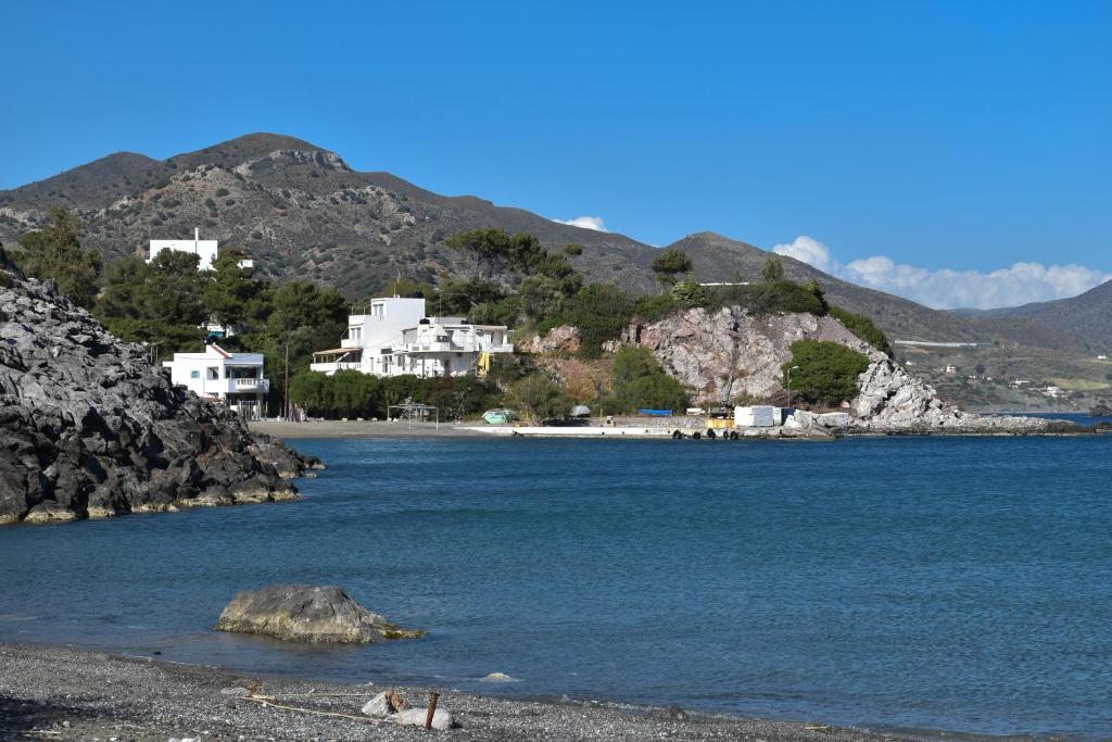 a group of people sitting on a beach near the water at Theaktis Homes in Kaloi Limenes