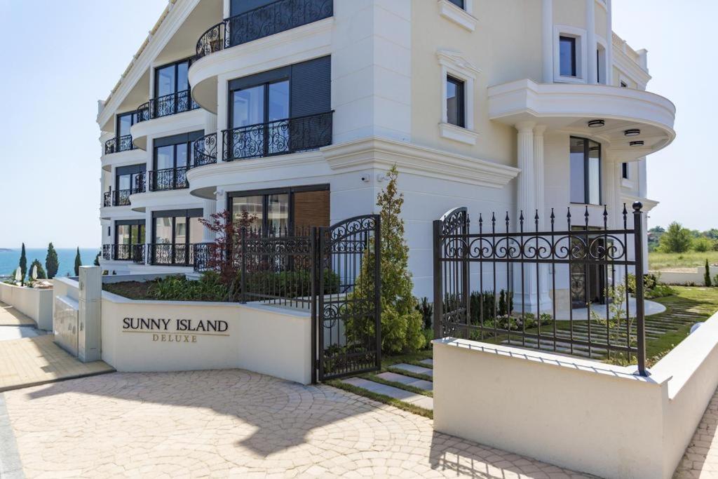 a large white house with a black fence at Azur Apartment Deluxe in Chernomorets