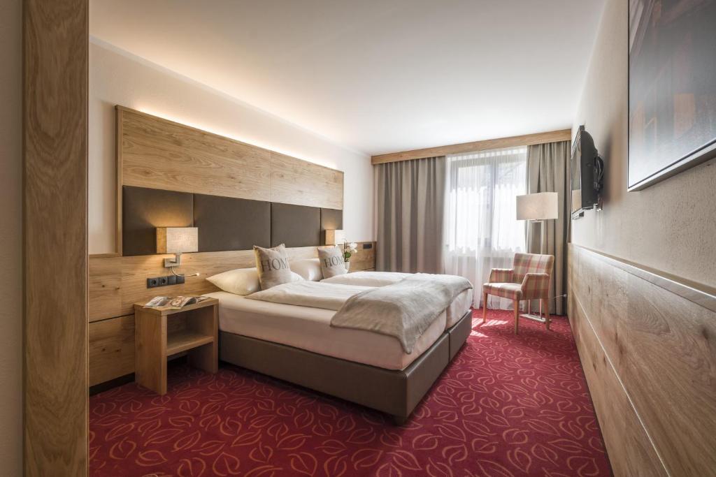 クーフシュタインにあるホテル アンドレアス ホファーの大きなベッドとテーブルが備わるホテルルームです。