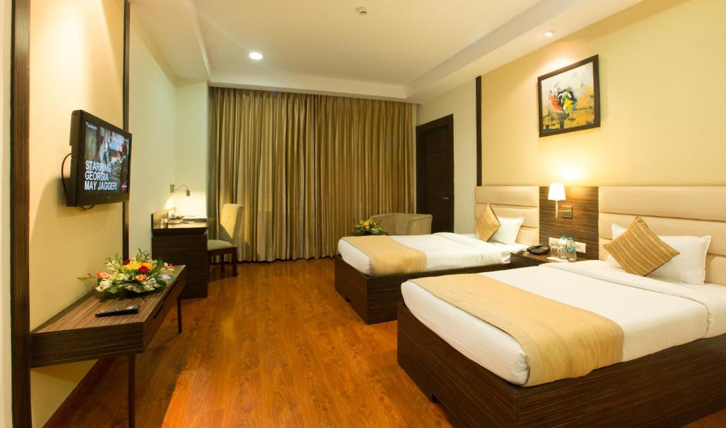 a hotel room with two beds and a television at Hyphen Premier-Business Hotel in Meerut