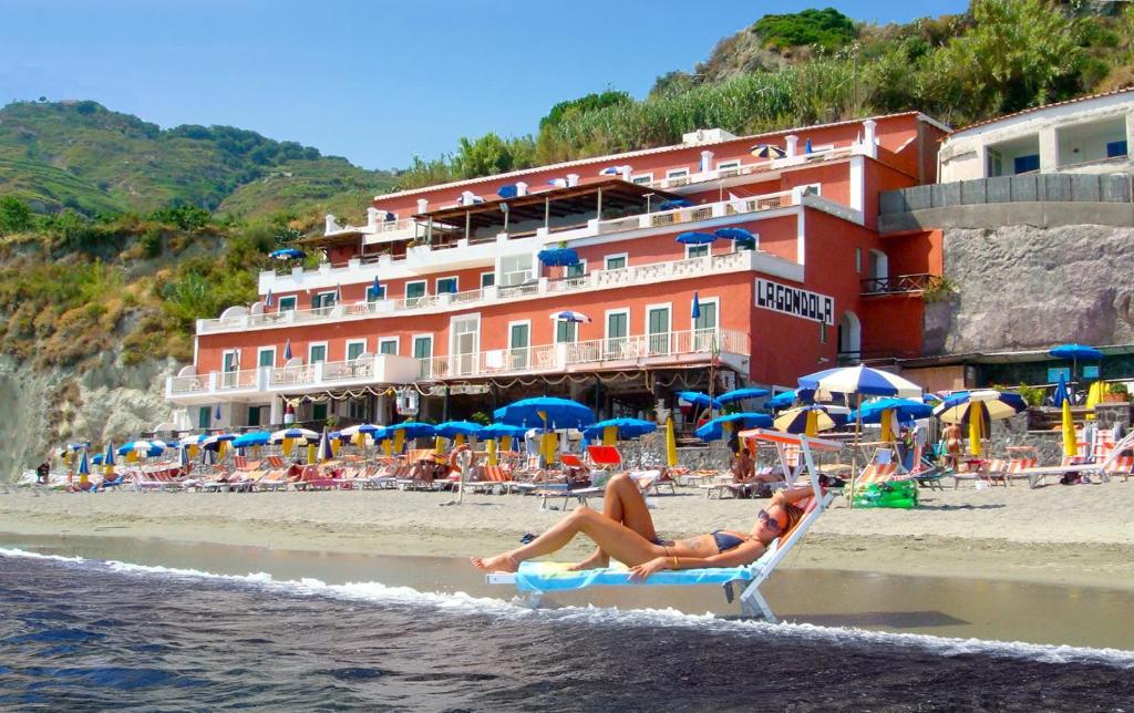 dwoje osób siedzących na leżakach na plaży w obiekcie Hotel La Gondola w mieście Ischia