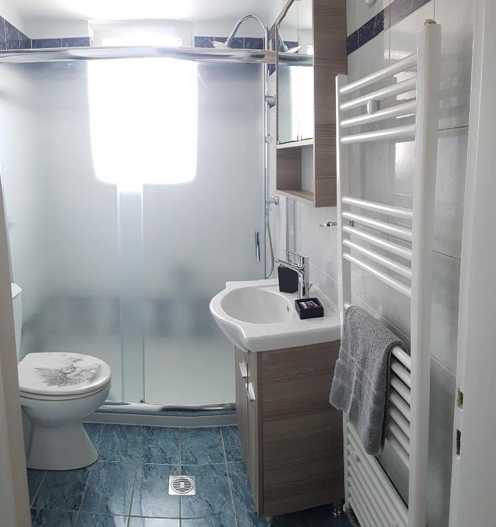 biała łazienka z toaletą i umywalką w obiekcie MAHE APARTMENT w mieście Wolos