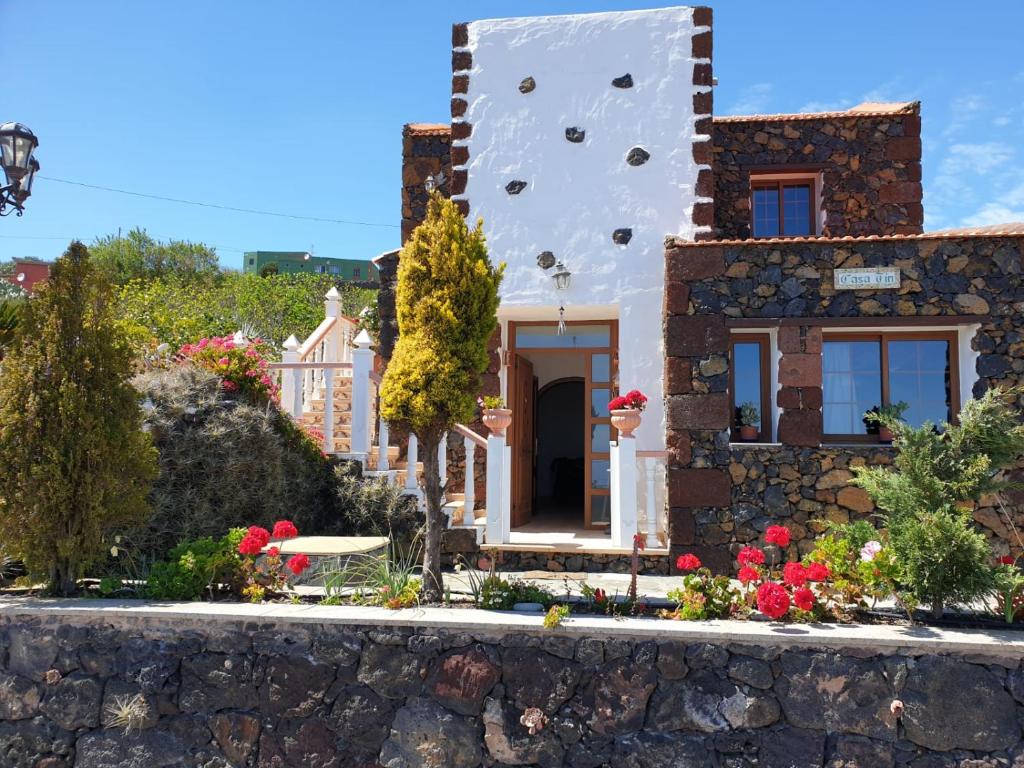 una casa con una pared de piedra y flores en CASA TIN, en Isora