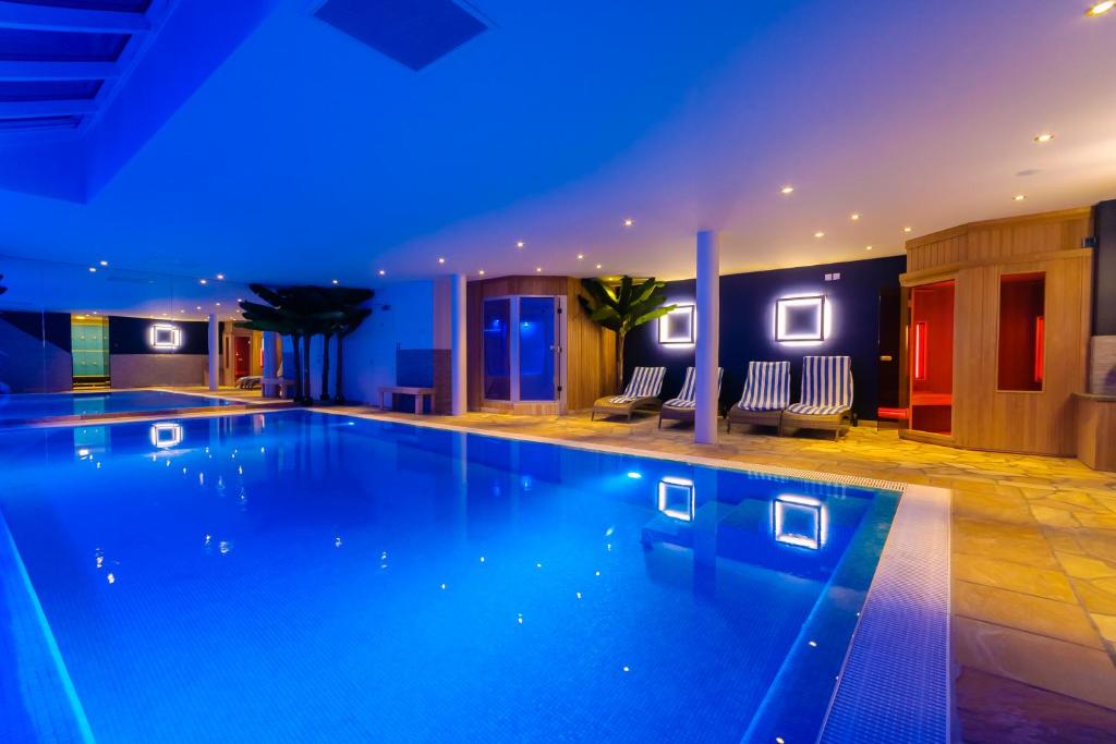 a swimming pool in a hotel with blue lighting at Hotel Pracha in Borgloon