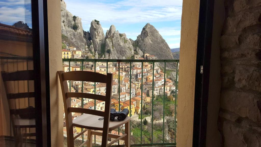 a black cat sitting on a chair looking out a window at Casa delle Stelle in Castelmezzano