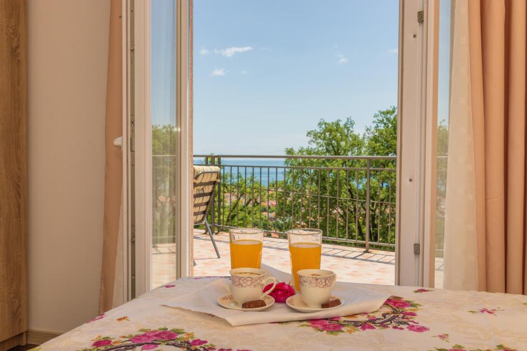 a table with two glasses of orange juice on a balcony at Villa Sunny Hill in Budva