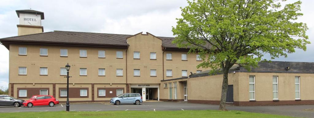 a large building with cars parked in a parking lot at Cairn Hotel in Bathgate