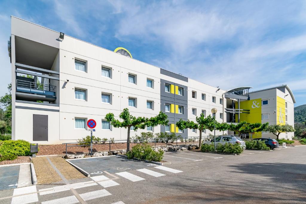 ein großes weißes Gebäude mit Parkplatz in der Unterkunft B&B HOTEL Marseille La Valentine in Marseille