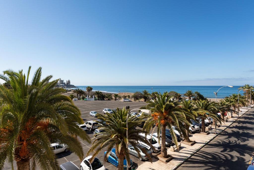 a row of cars parked in a parking lot with palm trees at 2 min Walk to Beach - Private Terrace - Some with Sea Views in La Playa de Arguineguín