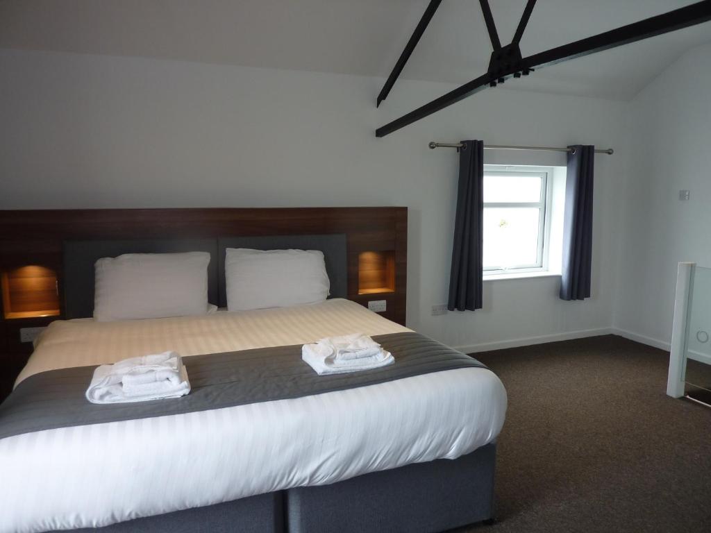 Oakwood Farm Mews Chester في تشيستر: غرفة نوم بسرير كبير عليها منشفتين