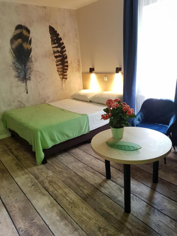 Un dormitorio con una cama y una mesa con flores. en Erdővarázs Panzió, en Lillafüred