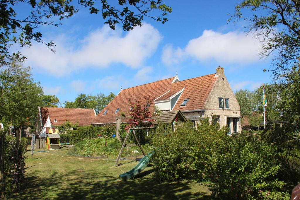 ein Haus mit einem Hof mit Schaukel in der Unterkunft Finistère in Oosterend