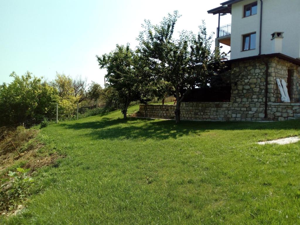 a grassy yard next to a house with a tree at Casa Del Grey in Balchik