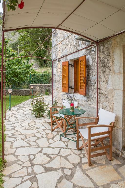 patio ze stołem, krzesłami i parasolem w obiekcie Villa Kastania w mieście Kastanéa