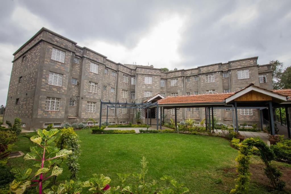 a large brick building with a green yard at Corat Africa Hotel in Nairobi