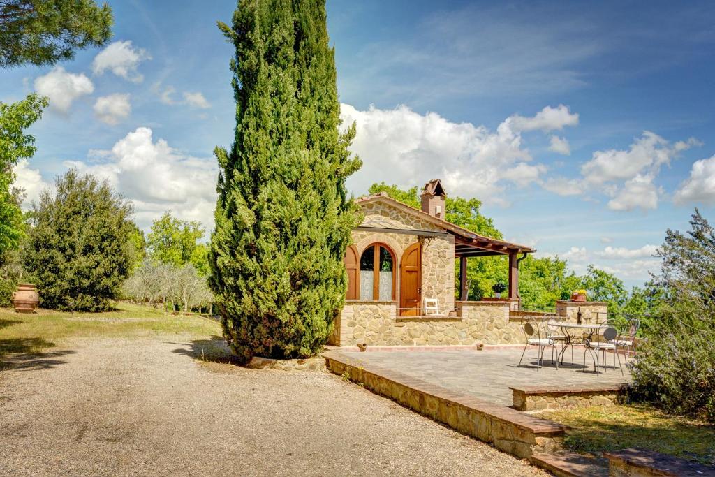 una casa con un gran árbol delante de ella en Villa Il Tollino en Sinalunga