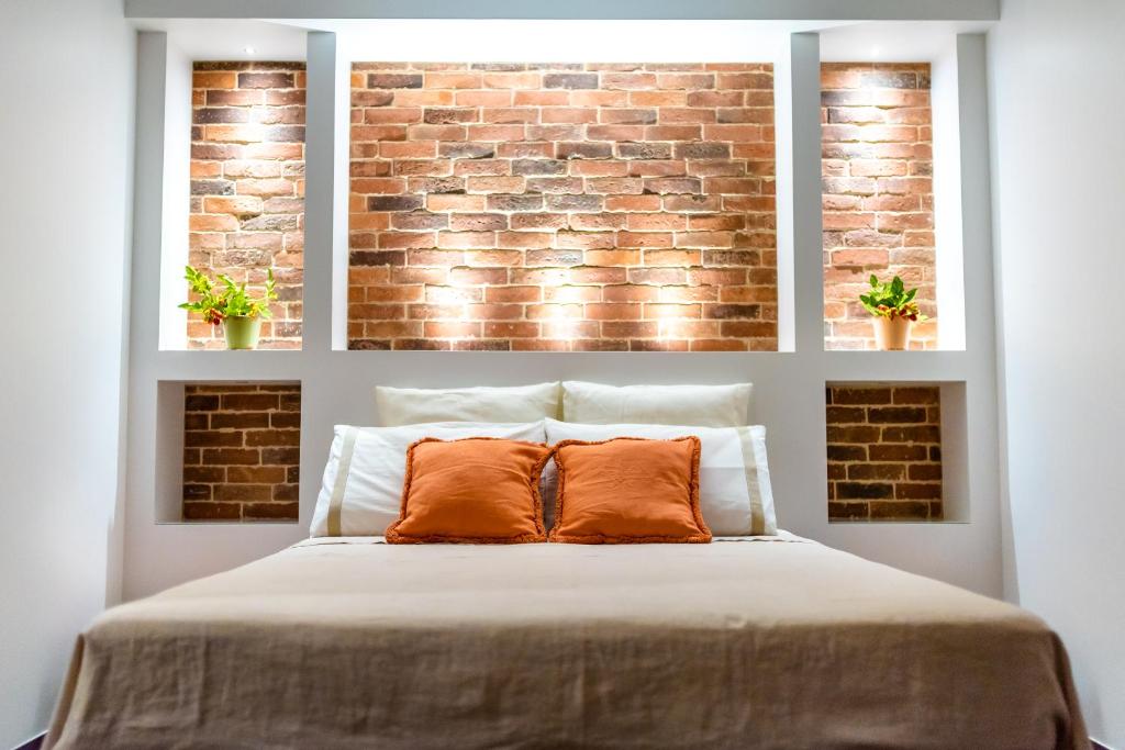 a bed with two pillows in front of a brick wall at B&B Villa Maria Pia in Monopoli