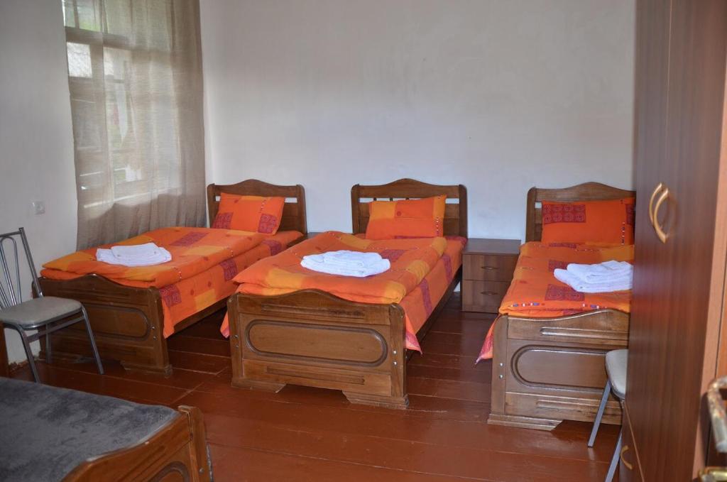2 bedden met oranje kussens in een kamer bij Vichnashi in Mestia