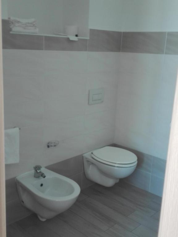 a white bathroom with a toilet and a sink at Hotel Conca d'Oro in Stalettì