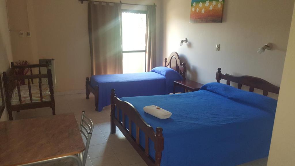 1 dormitorio con 2 camas con sábanas azules y mesa en Hotel Confort, en Santiago del Estero