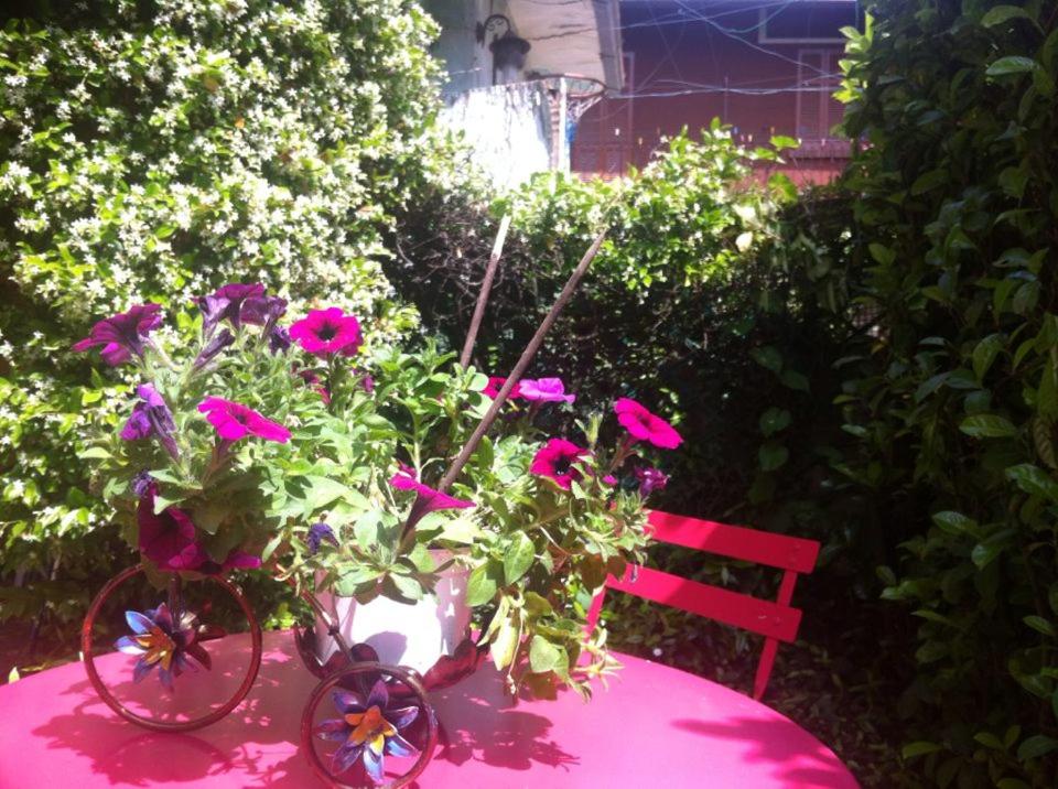 una mesa rosa con flores y un banco rojo en Appartamento Lago Maggiore, en Arona