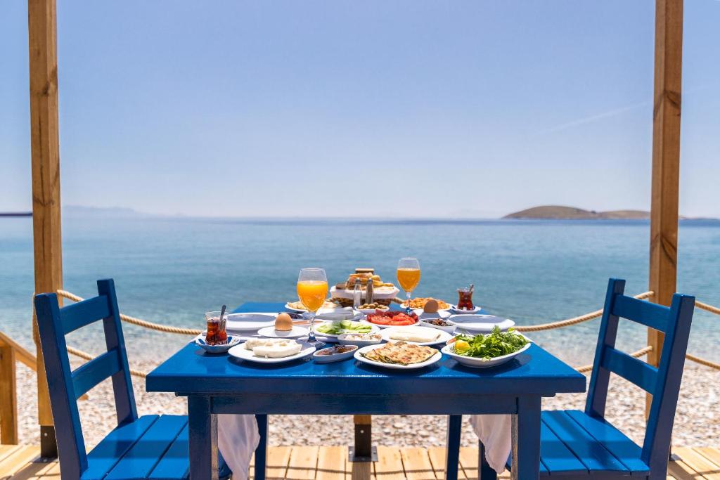 Karia Hotel Palamutbükü في موغلا: طاولة زرقاء مع طعام ومشروبات على الشاطئ