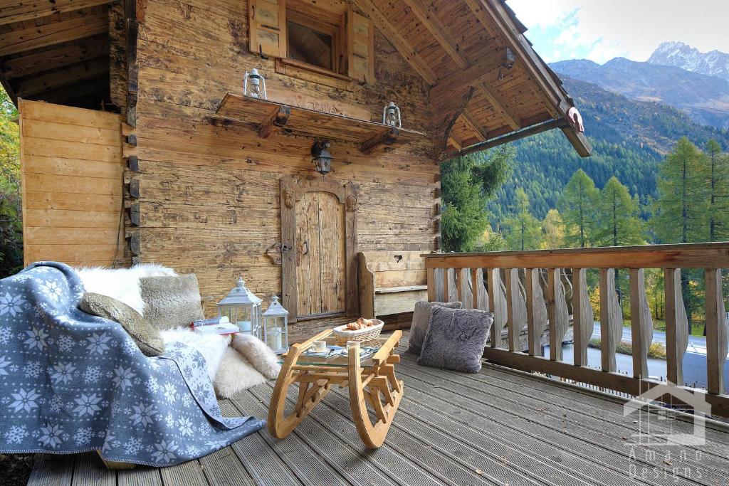 um alpendre de um chalé de madeira com uma mesa e cadeiras em Le Mazot de la Fis em Chamonix-Mont-Blanc