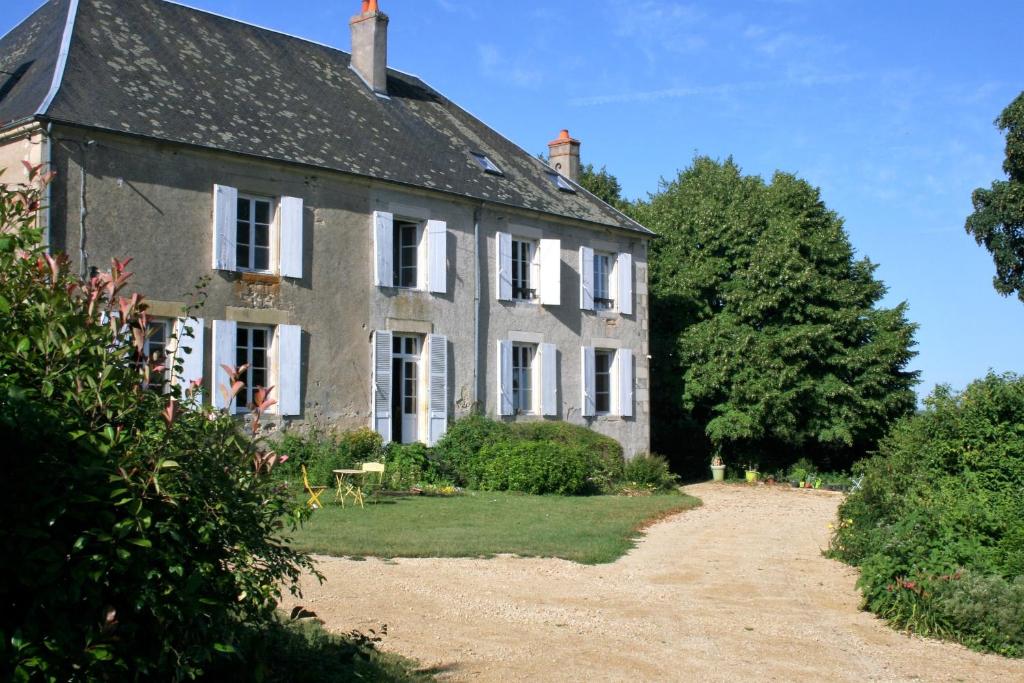 una vecchia casa in pietra con finestre e cespugli bianchi di Chambres d'hotes du Jay a La Guerche-sur-lʼAubois