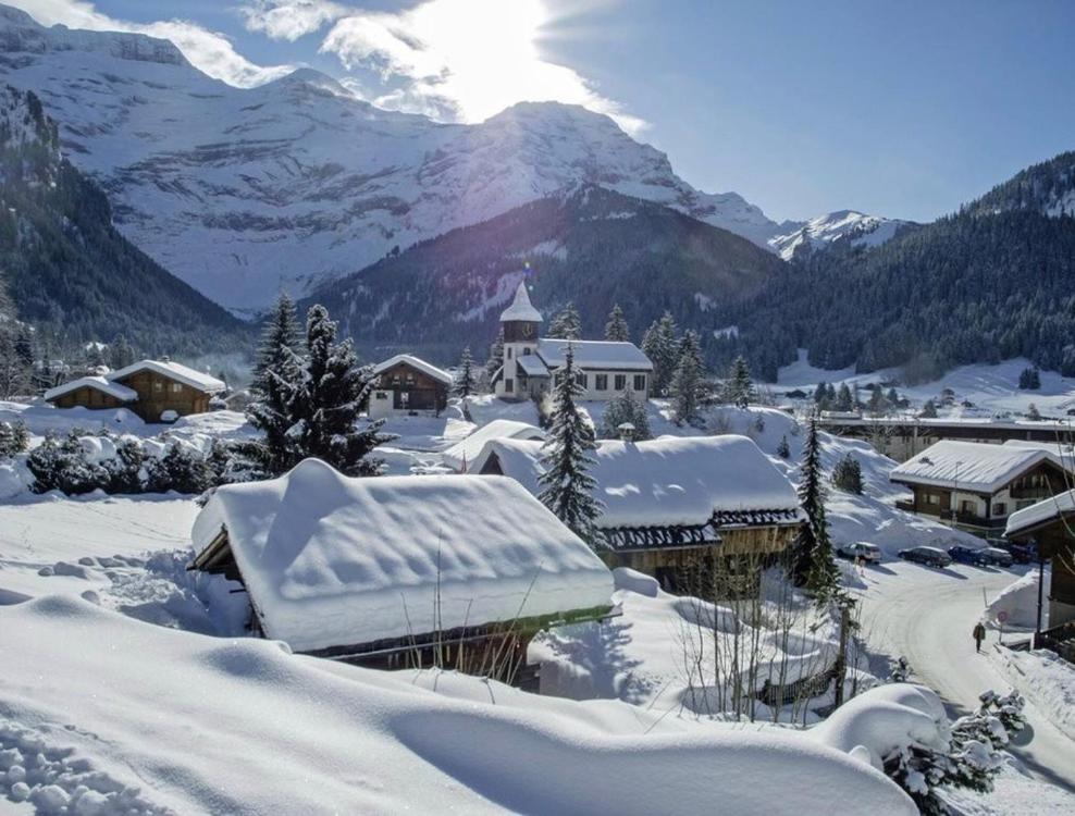 uma aldeia coberta de neve com montanhas ao fundo em Chalet Floriana em Les Diablerets