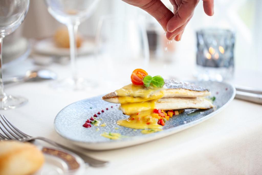 a person is sprinkling sauce on a plate of food at Grupotel Parc Natural & Spa in Playa de Muro