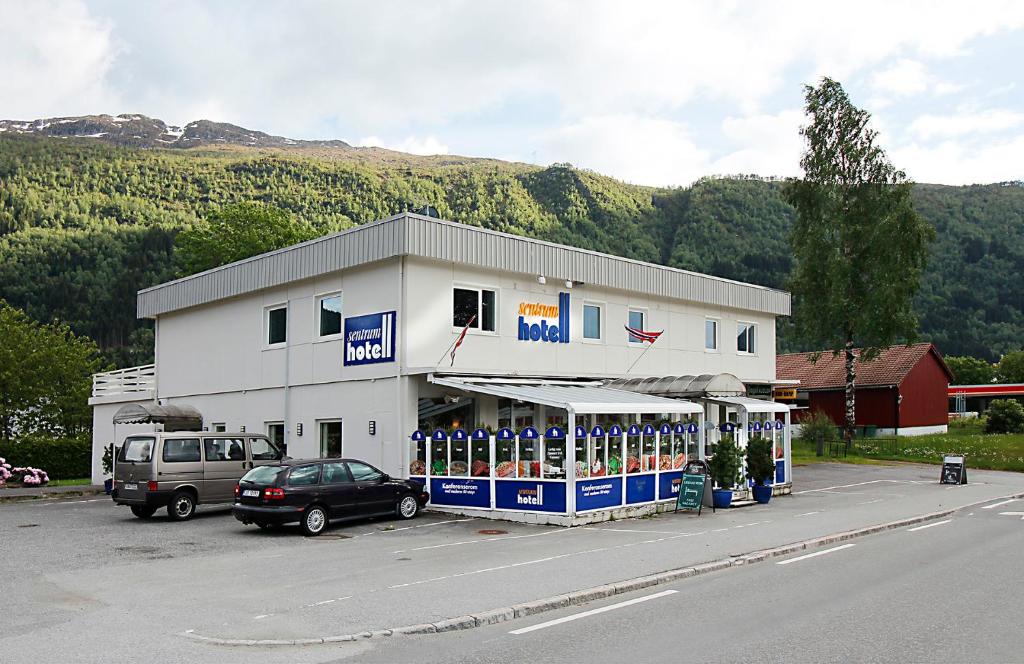 a building with a car parked in a parking lot at Sentrum Hotel in Nordfjordeid