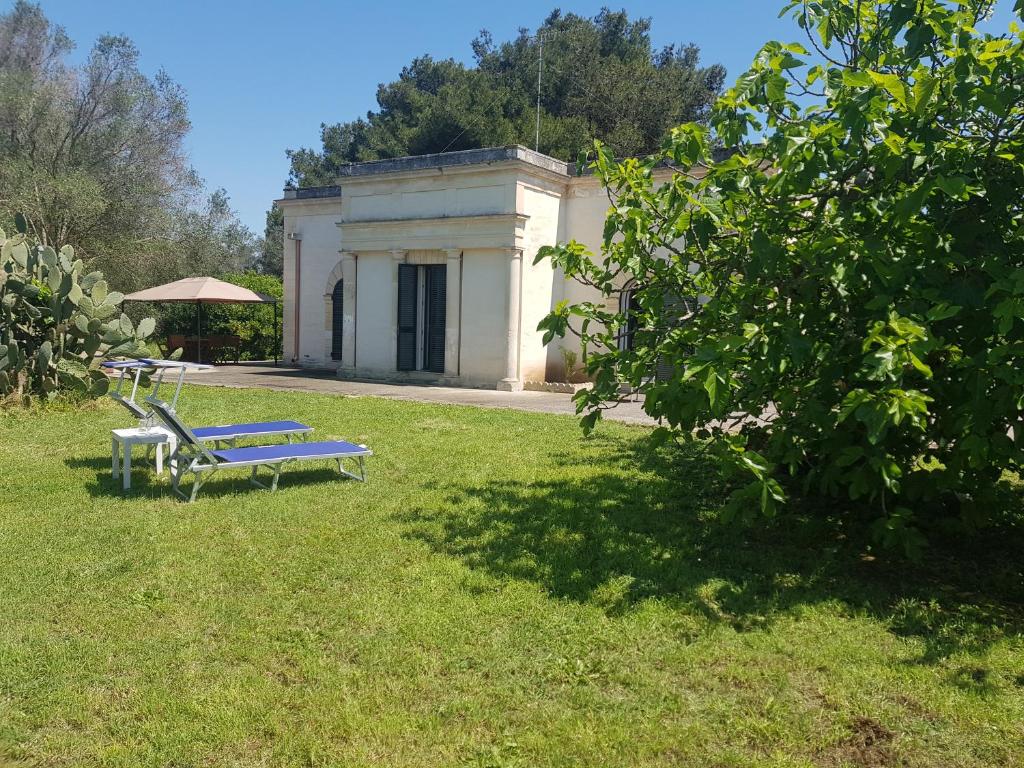 un banco azul sentado en el césped frente a un edificio en Il giardino del Salento - Lecce - Casa Vacanze, en Cavallino di Lecce