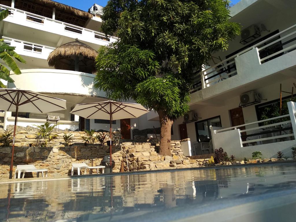 a swimming pool with umbrellas and a building at Jalyn's Resort Sabang in Puerto Galera