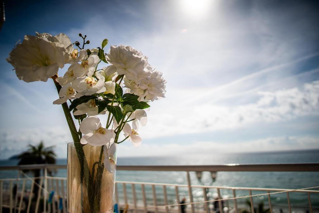 un jarrón lleno de flores blancas en una playa en Hotel West End en Alassio