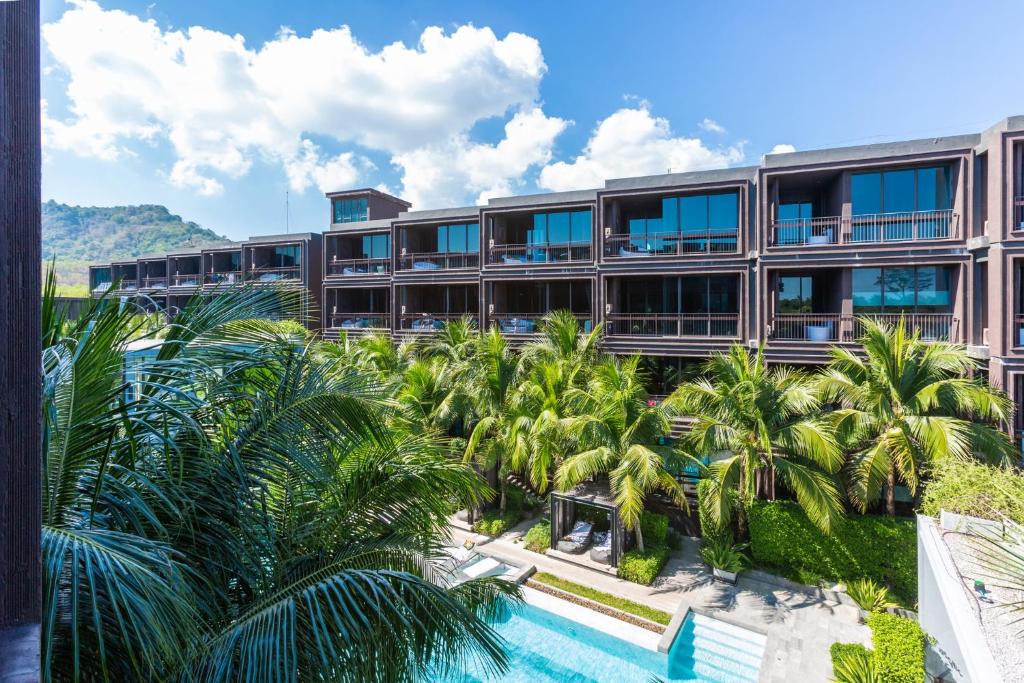 a building with palm trees and a swimming pool at Lucky Holidays in Saturdays Residence in Rawai Beach