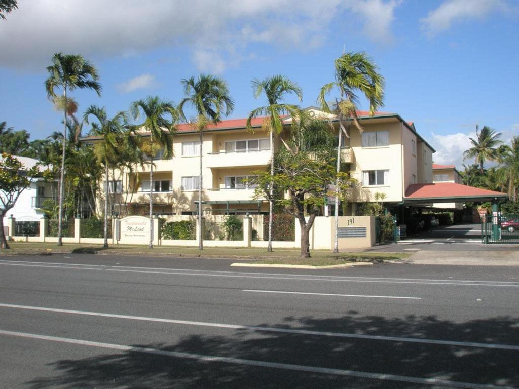 a building on the side of a street with palm trees at Tradewinds McLeod Holiday Apartments in Cairns