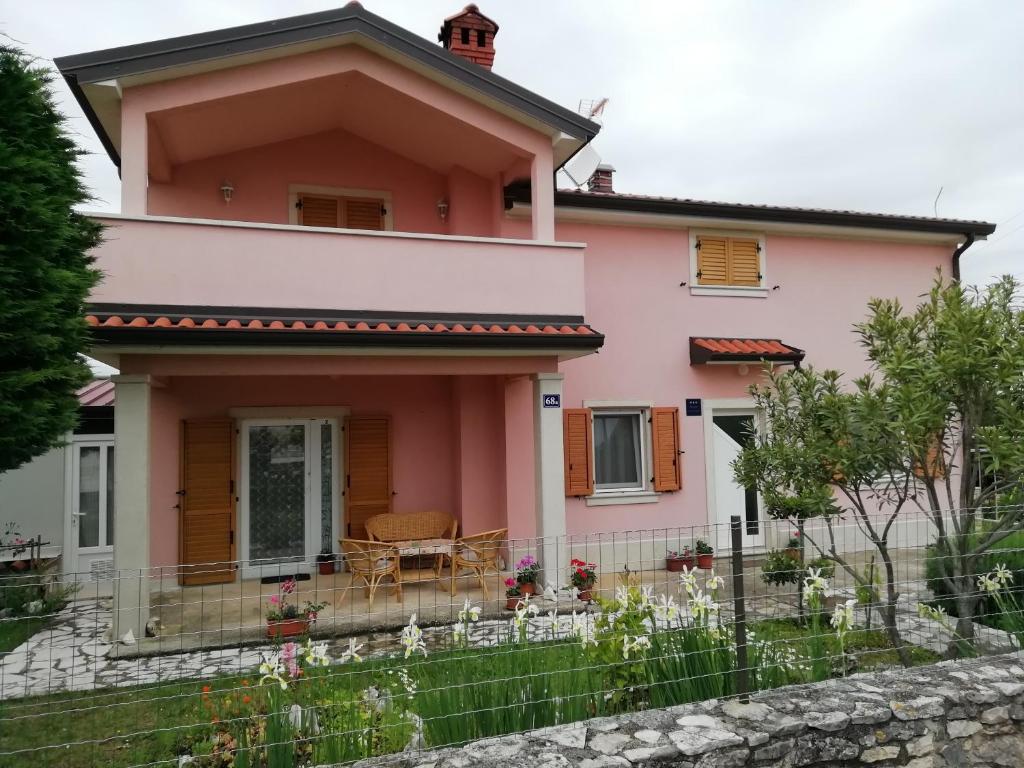 una casa rosa con una valla delante en Apartmani Vesna, en Buje