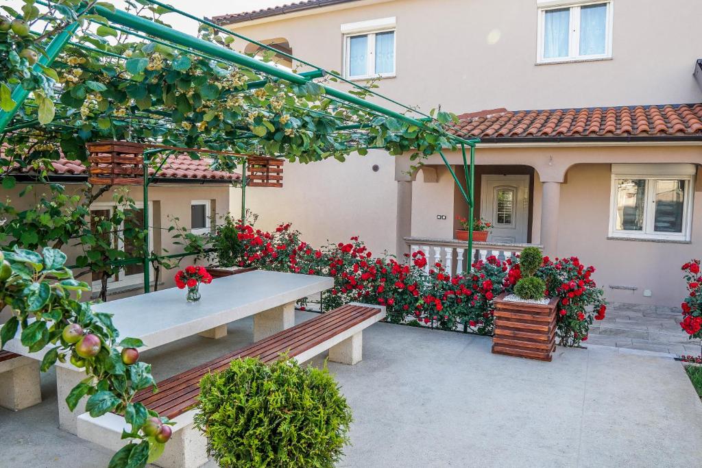 een patio met een bank voor een huis met rode bloemen bij Apartment Sunčica in Pula