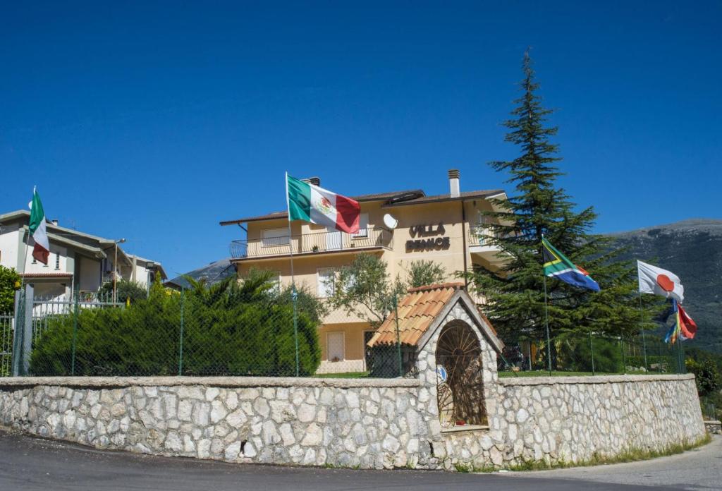 a building with flags in front of a stone wall at Villa Benice in Morino