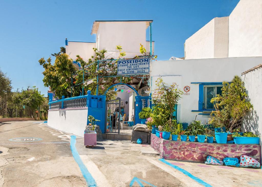 a building with blue doors and plants in front of it at Poseidon Apartment in Archangelos